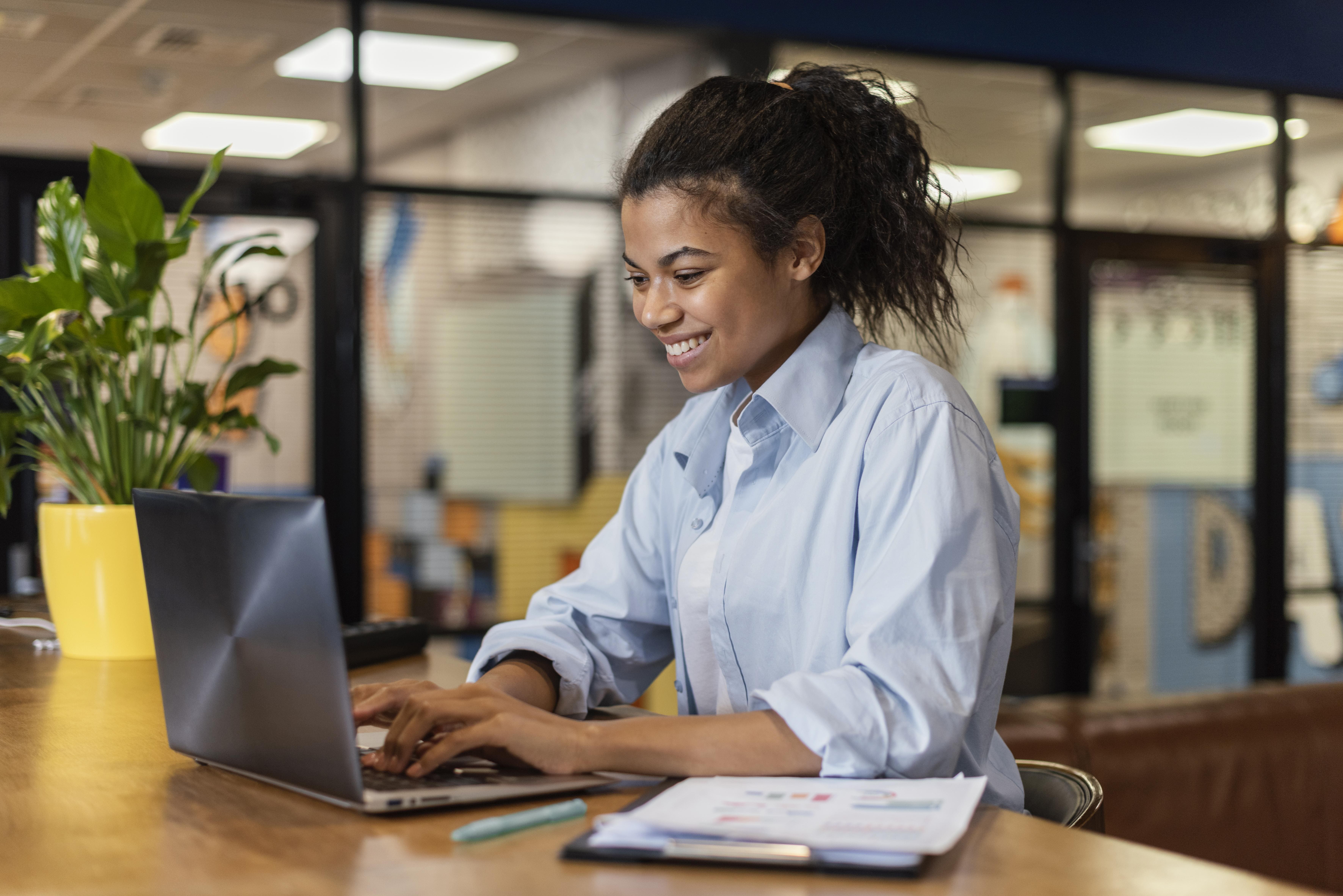 Microempreendedora compara planos de saúde MEI e individual no notebook, com orçamentos sobre a mesa