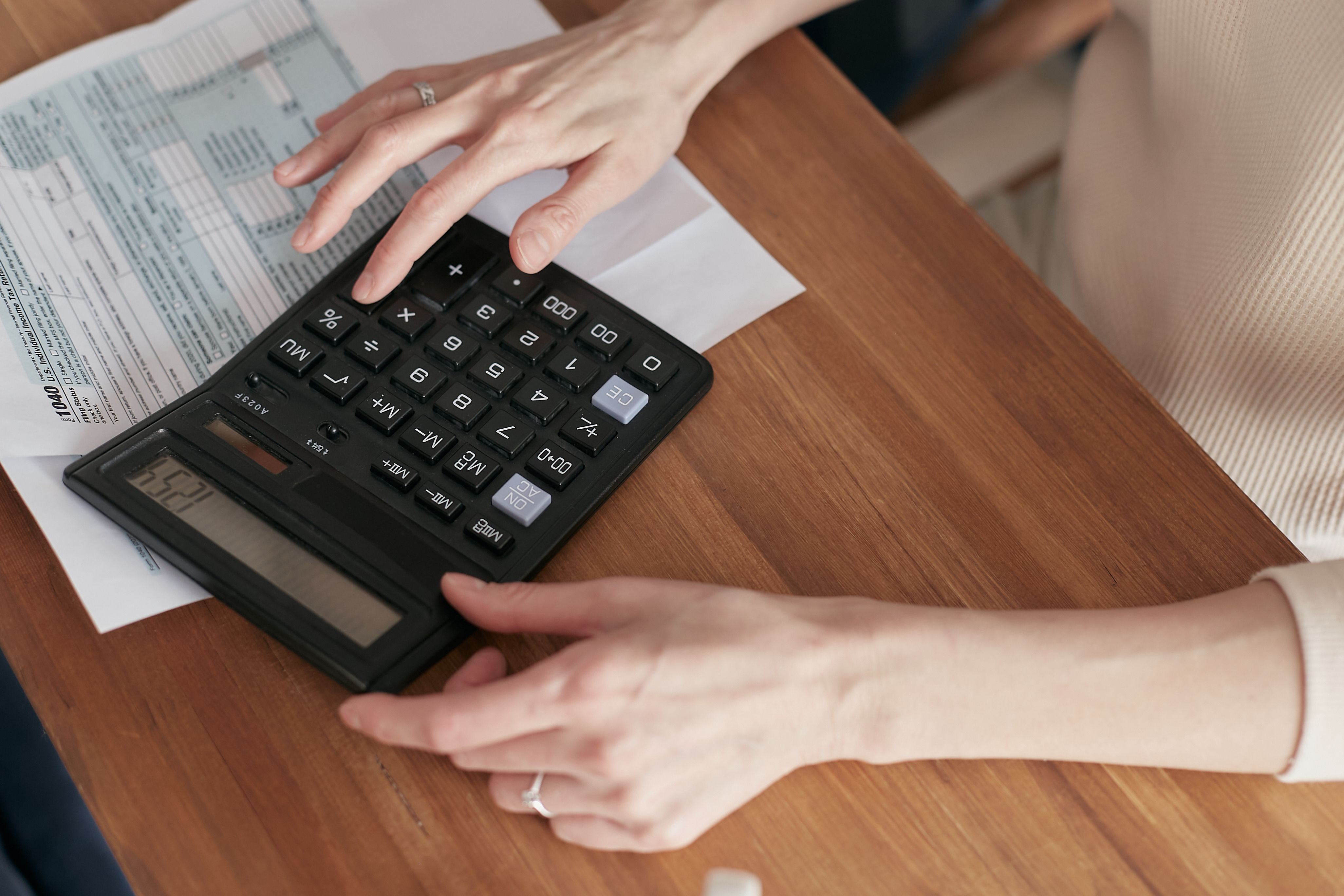 Mãos fazendo contas do plano de saúde em uma calculadora com a fatura ao lado