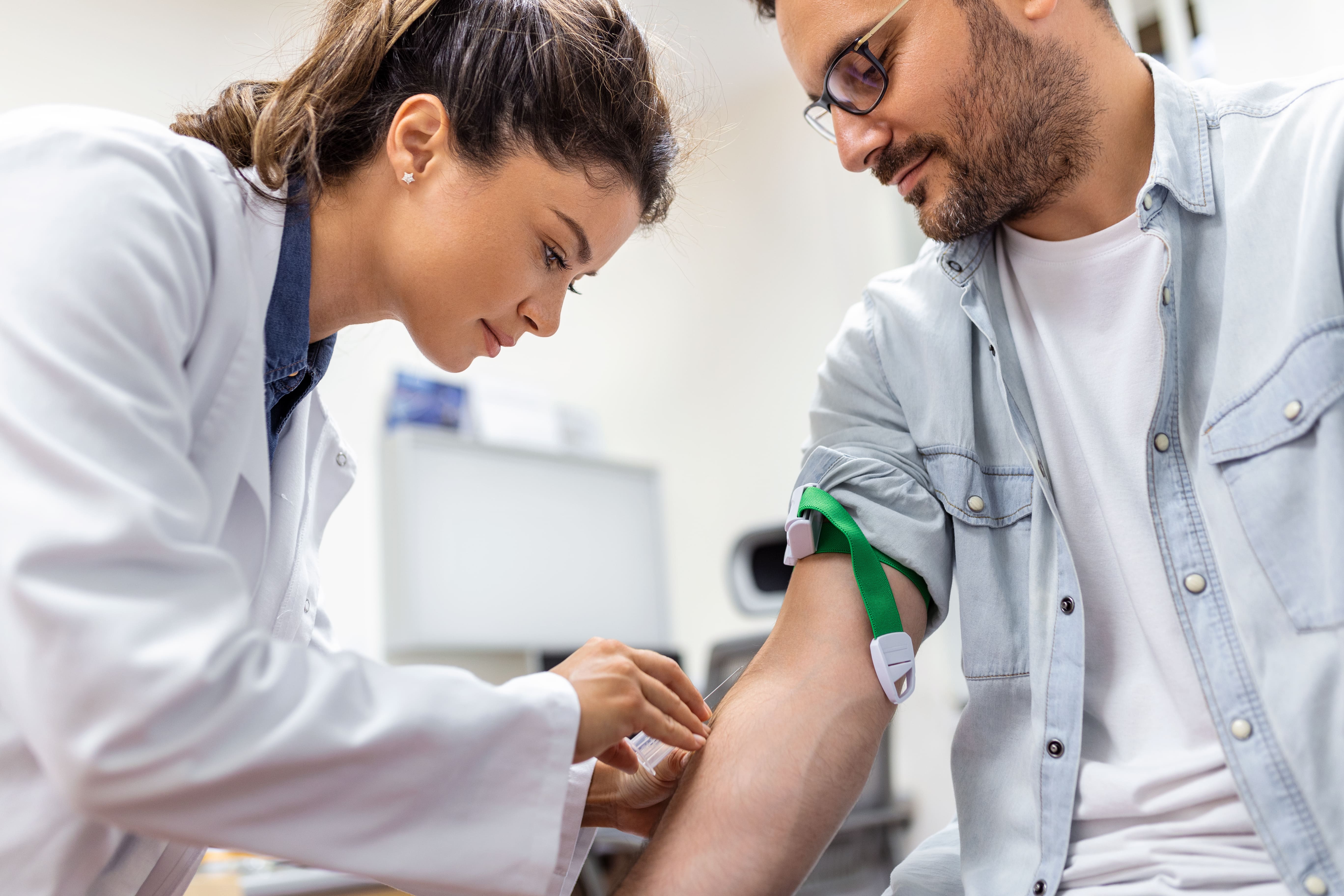 Profissional de saúde coletando sangue do braço de um paciente para exame laboratorial em um laboratório